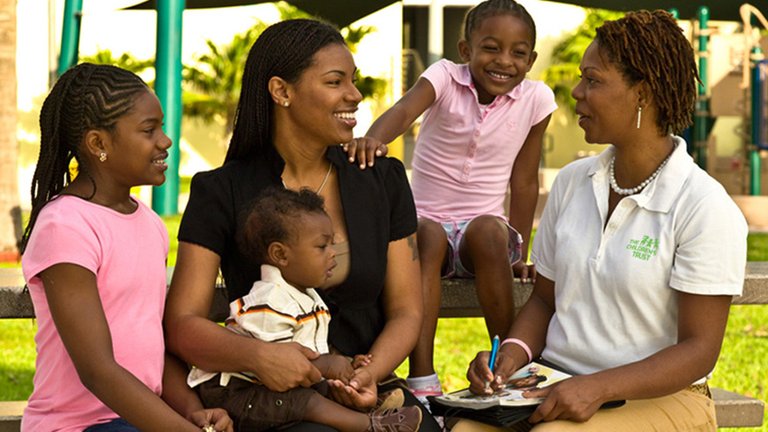 A mother and three children talk to a representative from The Children's Trust