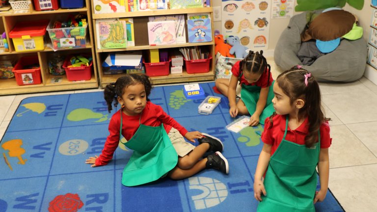 Photograph of three little girls playing on the floor in a classroom