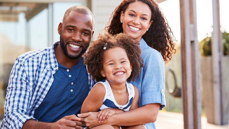 Family of three similing outdoors