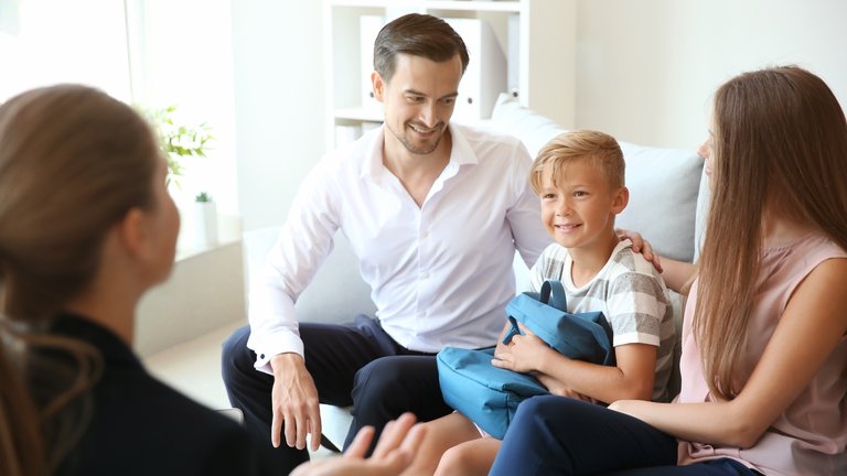 Smiling family with child talking to a professional in an office.