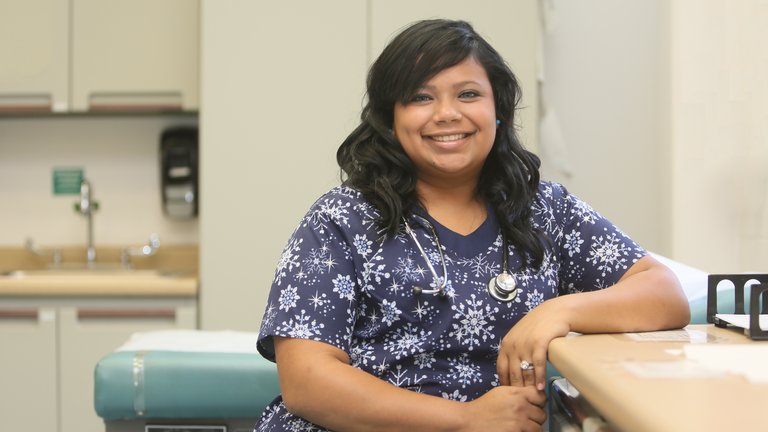 Smiling nurse in scrubs with stethoscope in a clinic.