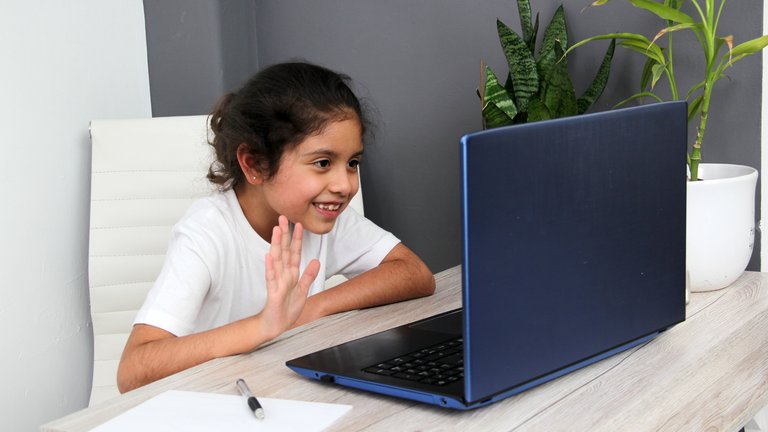 little girl waving to a computer screen
