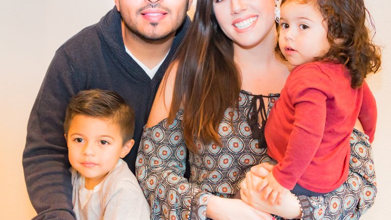 A smiling family of four hugging together