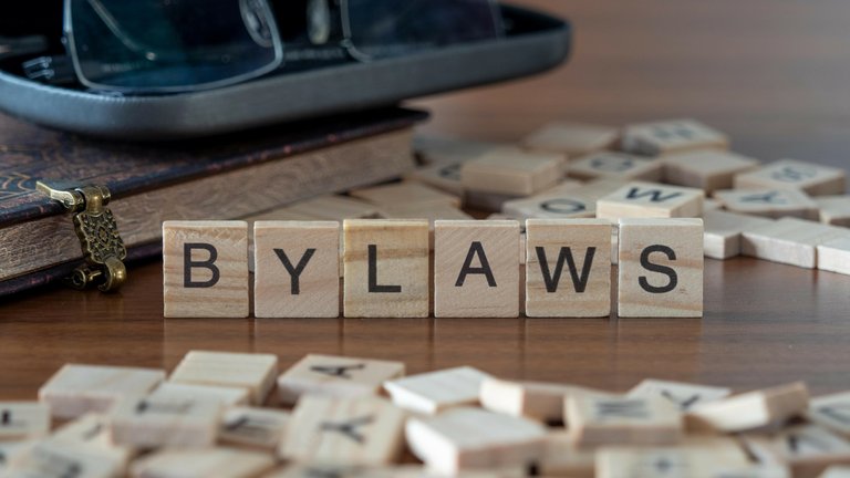Wooden tiles spelling 'BYLAWS' with a book and glasses nearby.