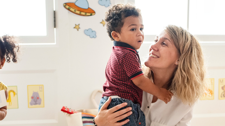 A group of adults and children playing in a kindergarten room floor